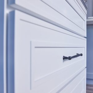Close-up of white kitchen cabinets with black handles.