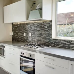 Modern kitchen with gray countertops and mosaic backsplash.