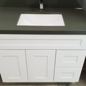 White bathroom vanity with green countertop and modern faucet.