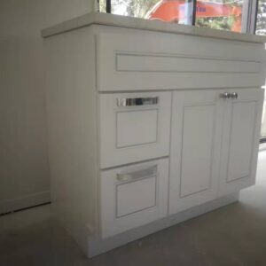White kitchen cabinet with drawers and countertop in a bright room.