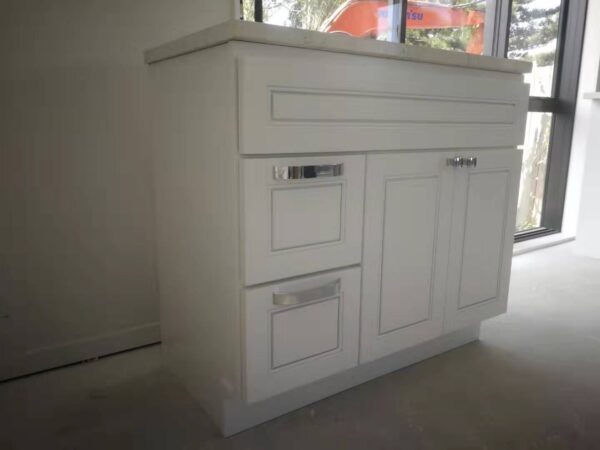 White kitchen cabinet with drawers and countertop in a bright room.