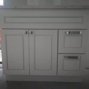 White kitchen cabinet with drawers and doors, against a window.