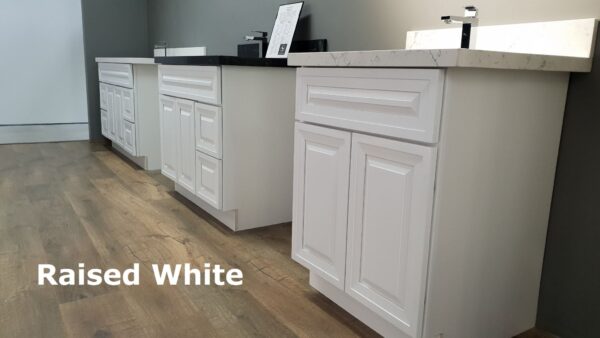 White kitchen cabinets with marble countertops and wood flooring.