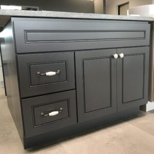 Grey kitchen island with drawers and granite countertop.