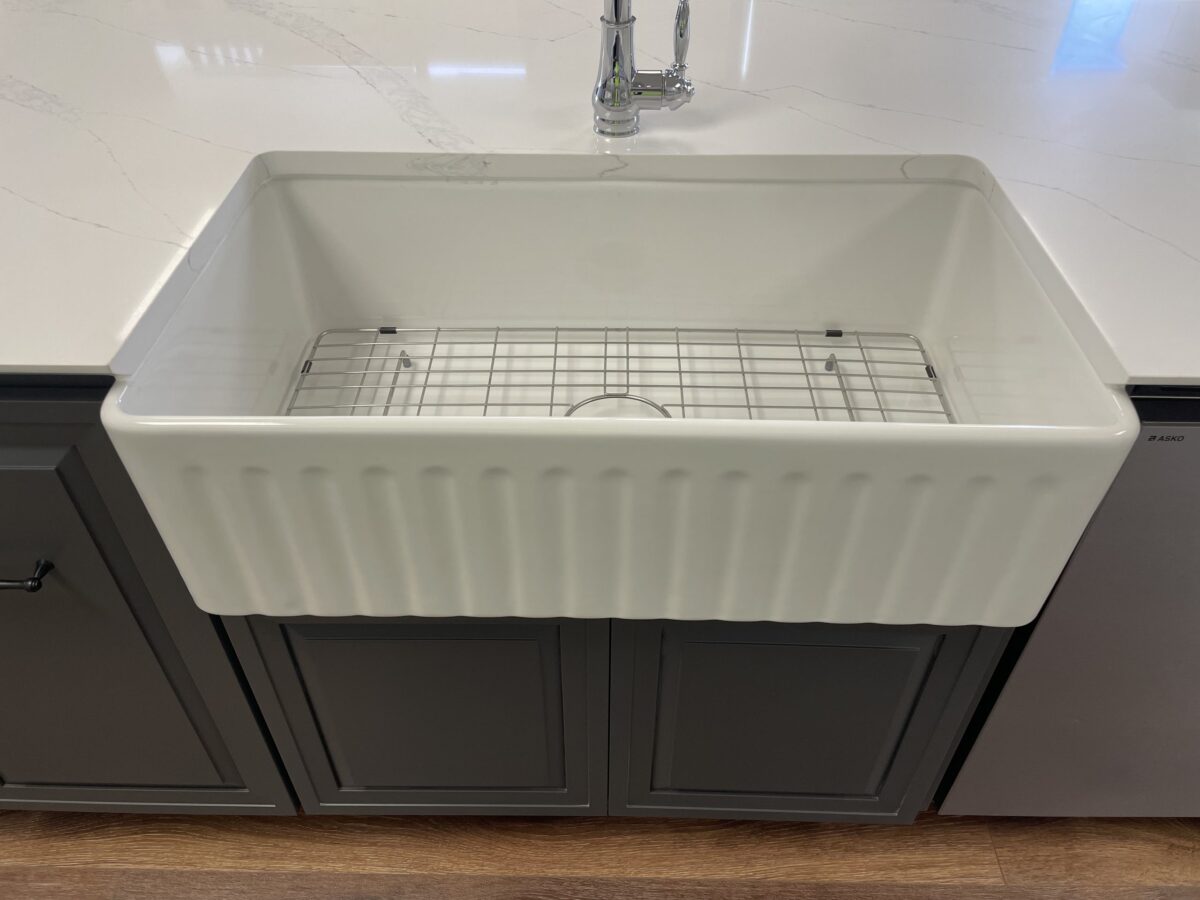 Farmhouse kitchen sink with grid, set in a marble countertop.