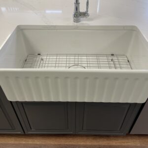 Farmhouse kitchen sink with grid, set in a marble countertop.