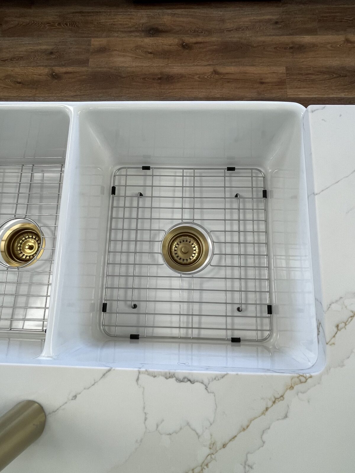 White kitchen sink with metal grid and drain.