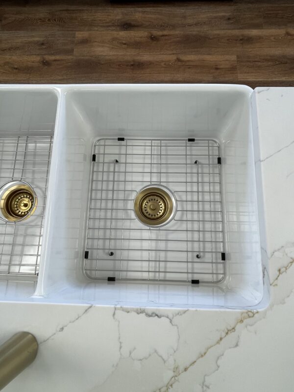 White kitchen sink with metal grid and drain.