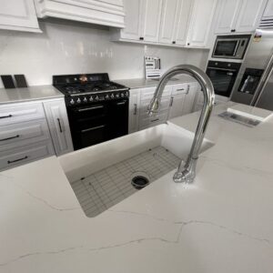 Modern kitchen with white cabinets and stainless steel appliances.