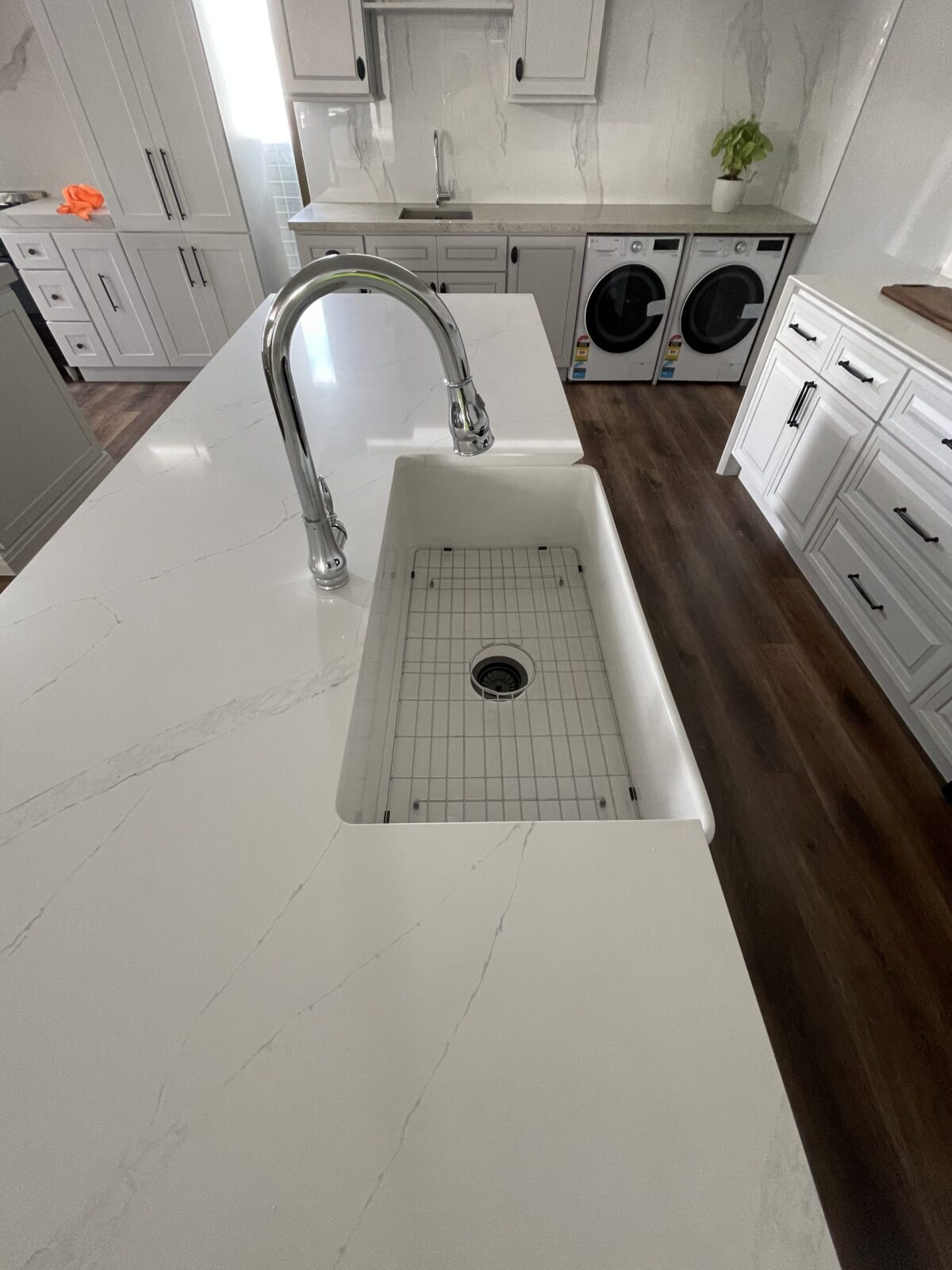 Modern kitchen with marble countertop, sink, and laundry appliances.