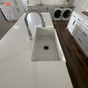 Modern kitchen with marble countertop, sink, and laundry appliances.