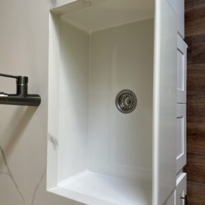 White kitchen sink with modern faucet on wooden countertop.