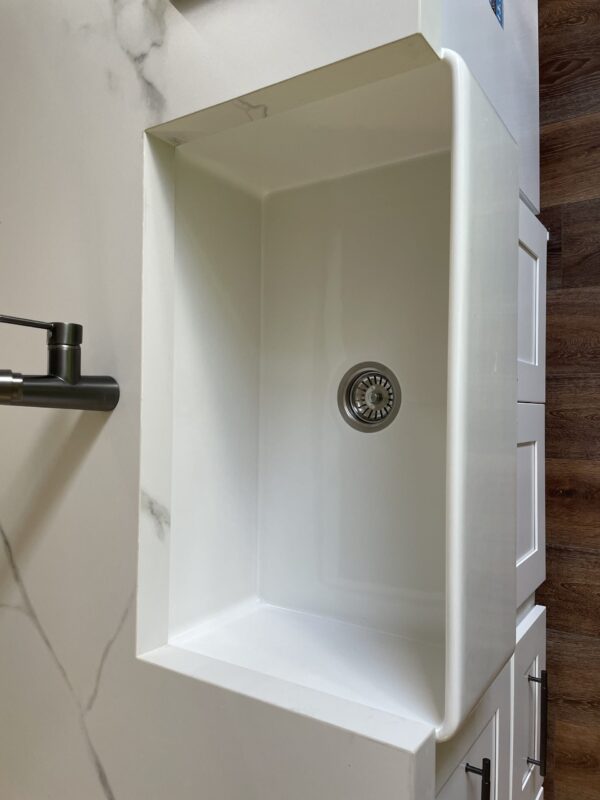 White kitchen sink with modern faucet on wooden countertop.