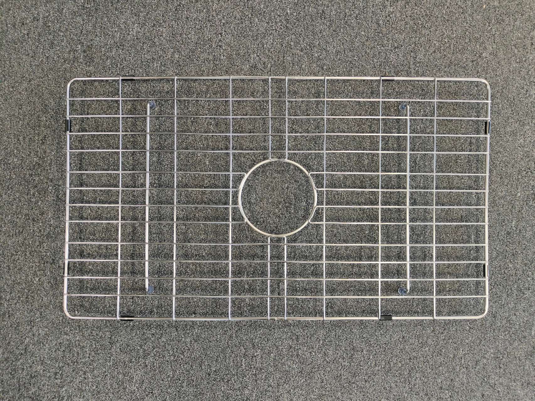 Metal sink protector on a gray surface.