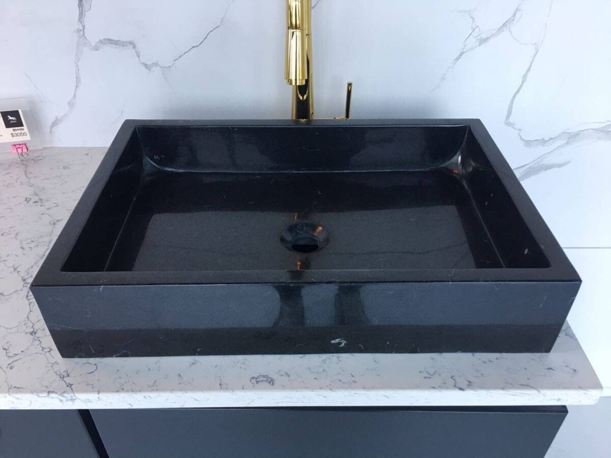 Black marble sink on a white marble countertop.
