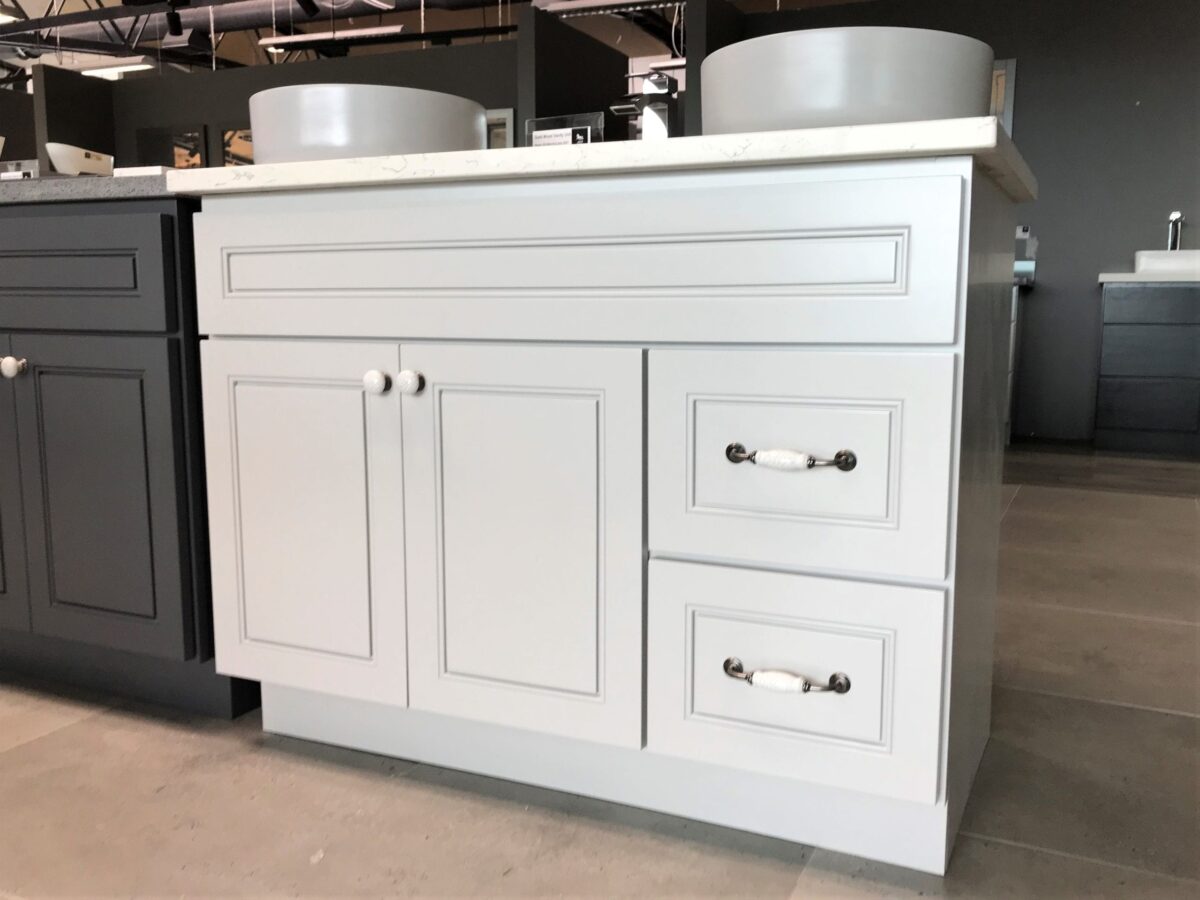 Light gray kitchen cabinet with drawers and round handles.
