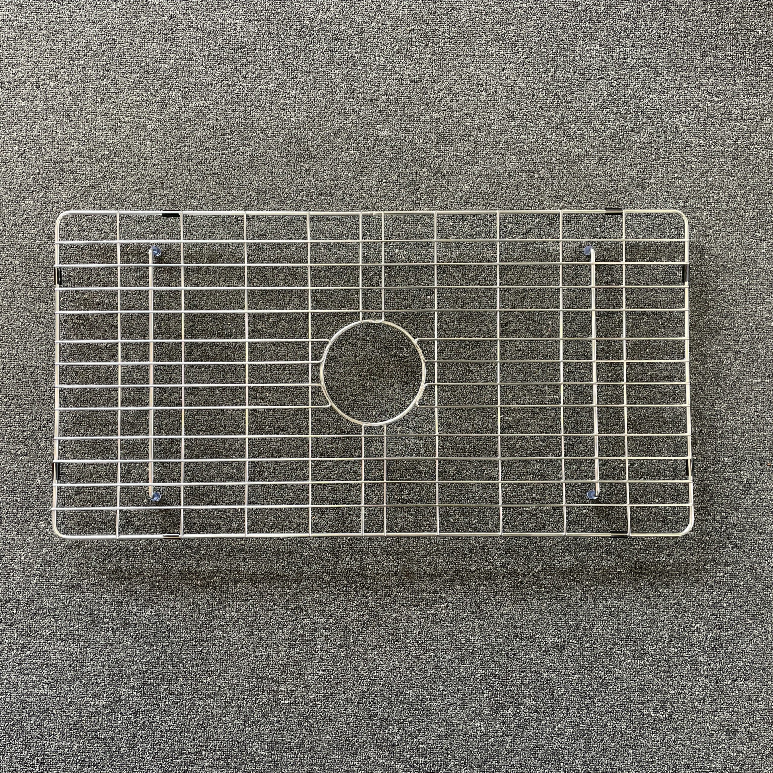 Stainless steel sink grid on a textured surface.
