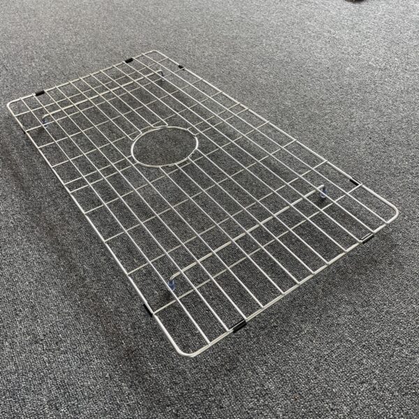 Stainless steel sink grid on gray carpet.