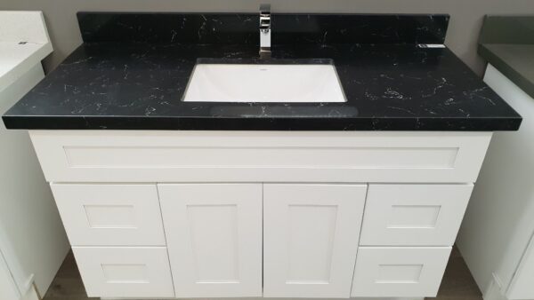 White bathroom vanity with black countertop and sink.