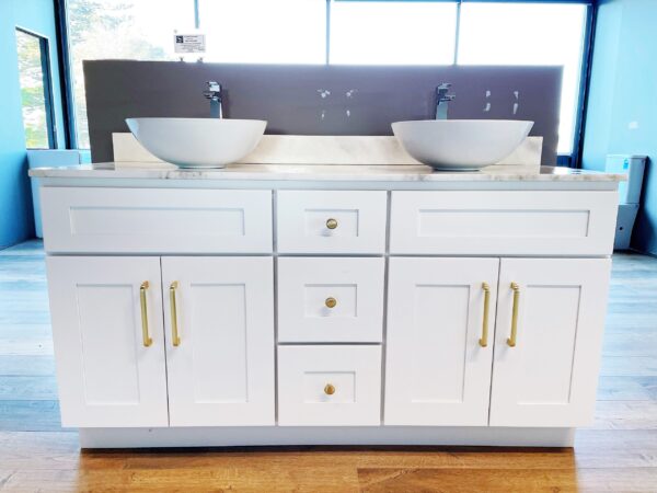 White bathroom vanity with dual sinks and gold handles.