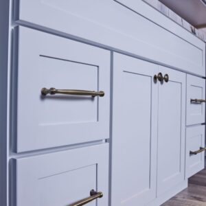 White kitchen cabinets with brass handles and knobs.