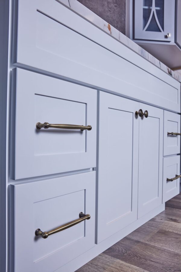 White kitchen cabinets with brass handles and knobs.