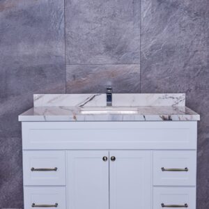 White bathroom vanity with marble countertop against gray stone wall.