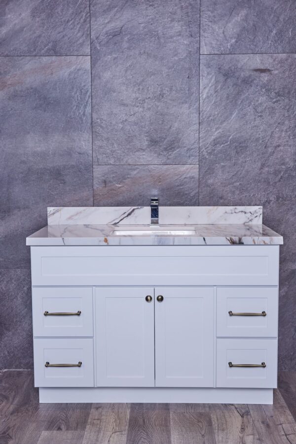 White bathroom vanity with marble countertop against gray stone wall.