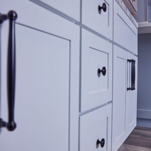 White kitchen cabinets with black handles, close-up view.