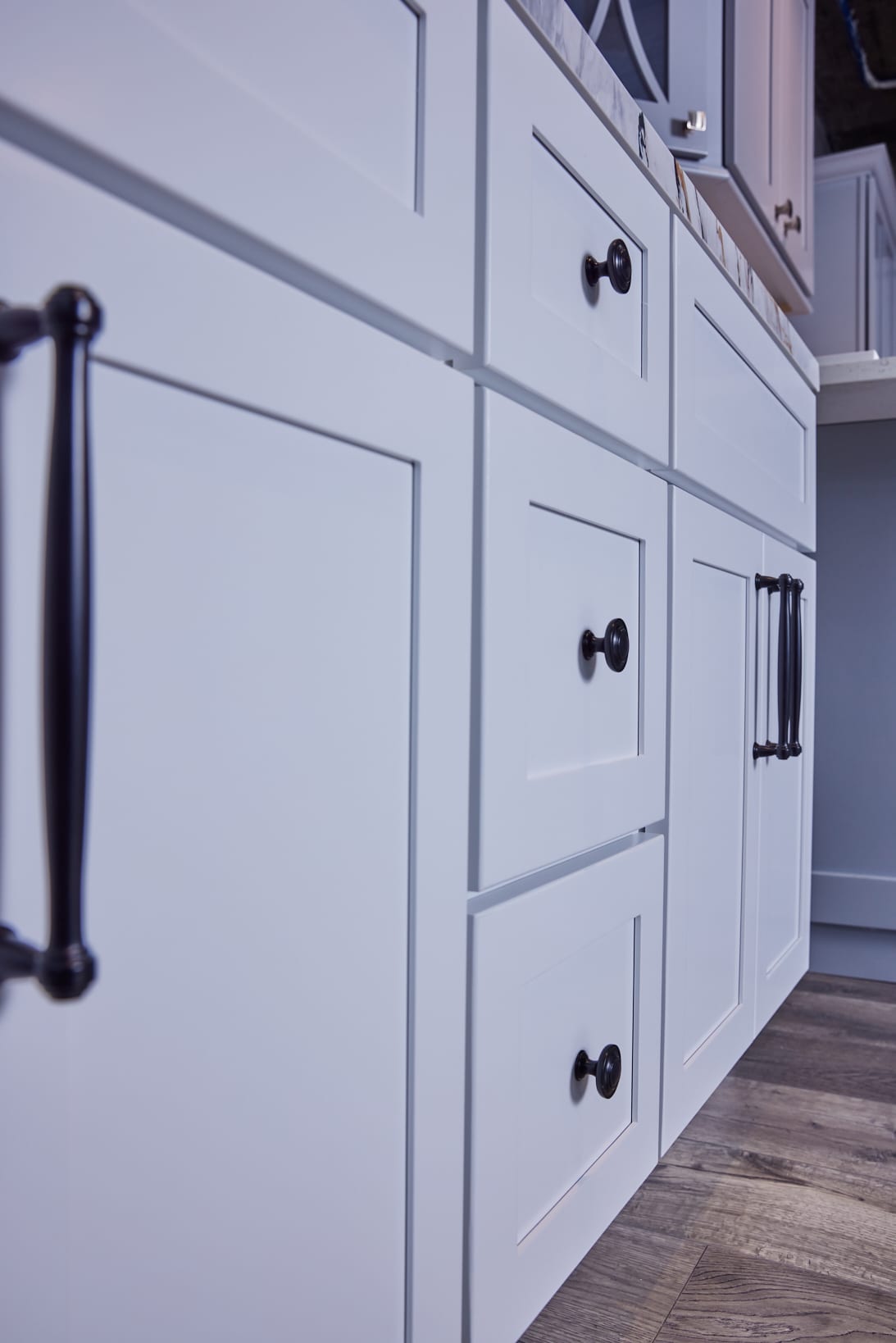 White kitchen cabinets with black handles, close-up view.