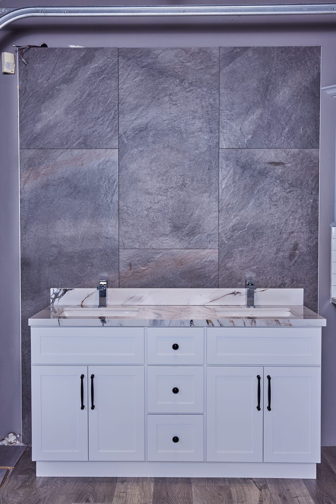 White bathroom vanity with marble countertop against gray stone wall.