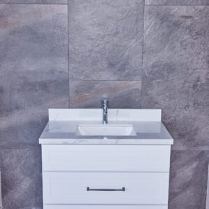 White bathroom vanity with sink against gray tiled wall.