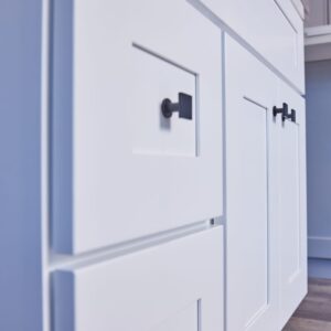 White kitchen cabinets with black handles, close-up view.