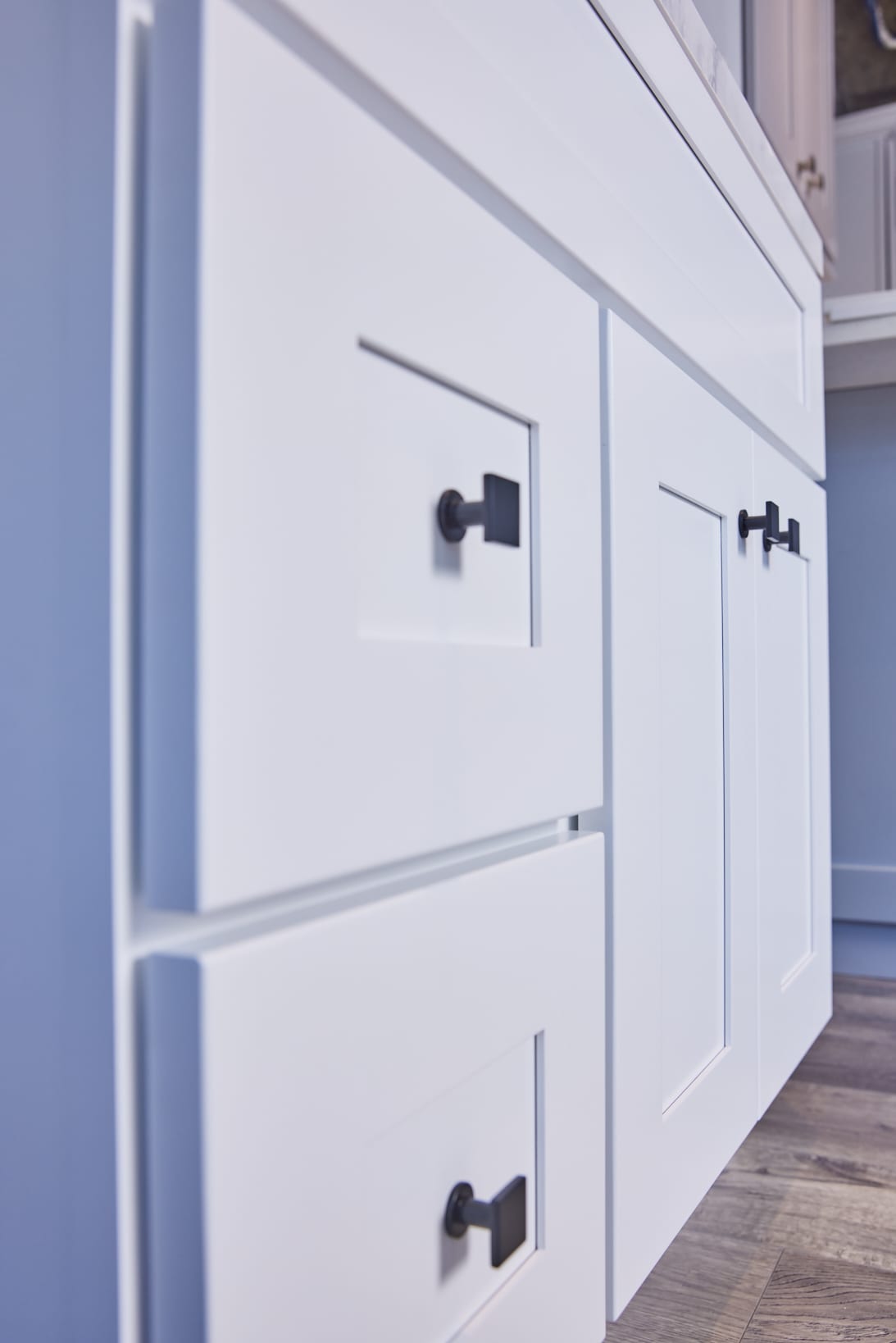 White kitchen cabinets with black handles, close-up view.