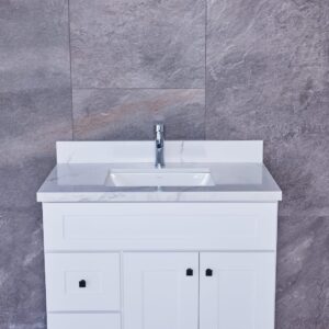 White bathroom vanity with marble countertop and modern faucet against gray tiled wall.