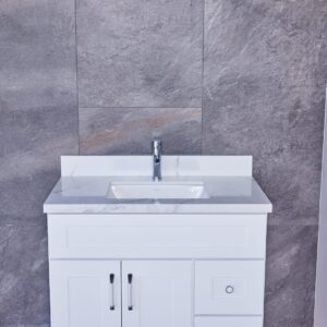 White bathroom vanity with marble countertop against gray stone wall.