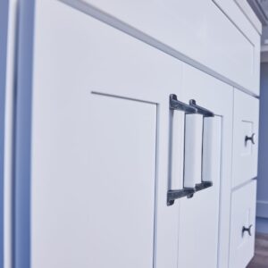 White kitchen cabinet with modern black handles.