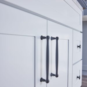 White kitchen cabinet with black handles, close-up view.