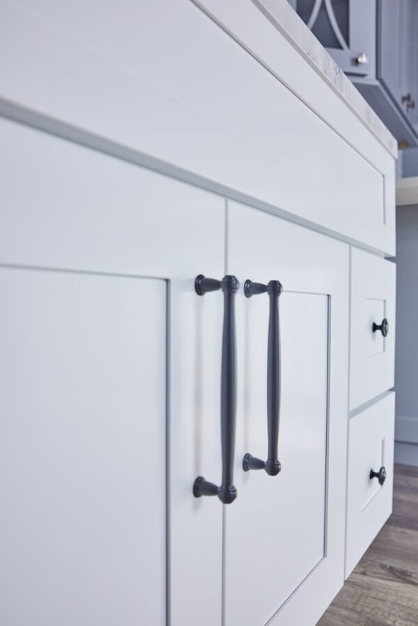 White kitchen cabinet with black handles, close-up view.