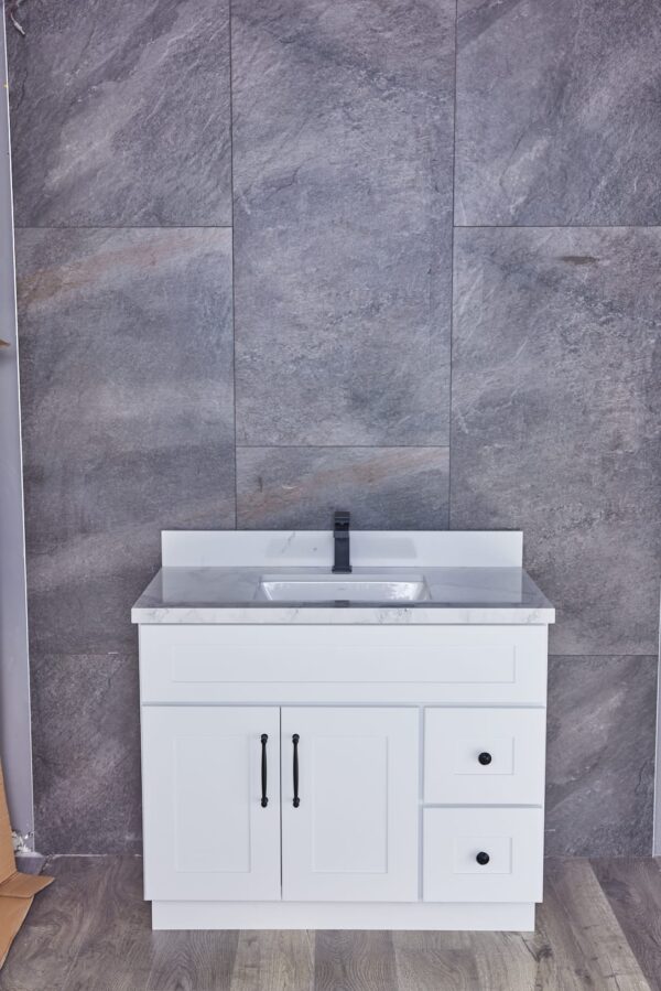 White bathroom vanity with marble countertop against gray tiled wall.