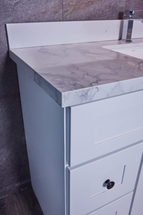 White bathroom vanity with marble countertop and modern faucet.