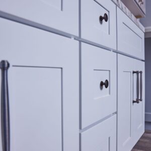 White kitchen cabinets with black handles, close-up view.