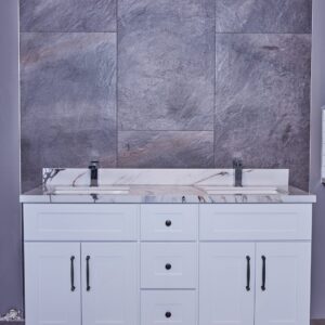 White bathroom vanity with marble countertop and gray tiled wall background.
