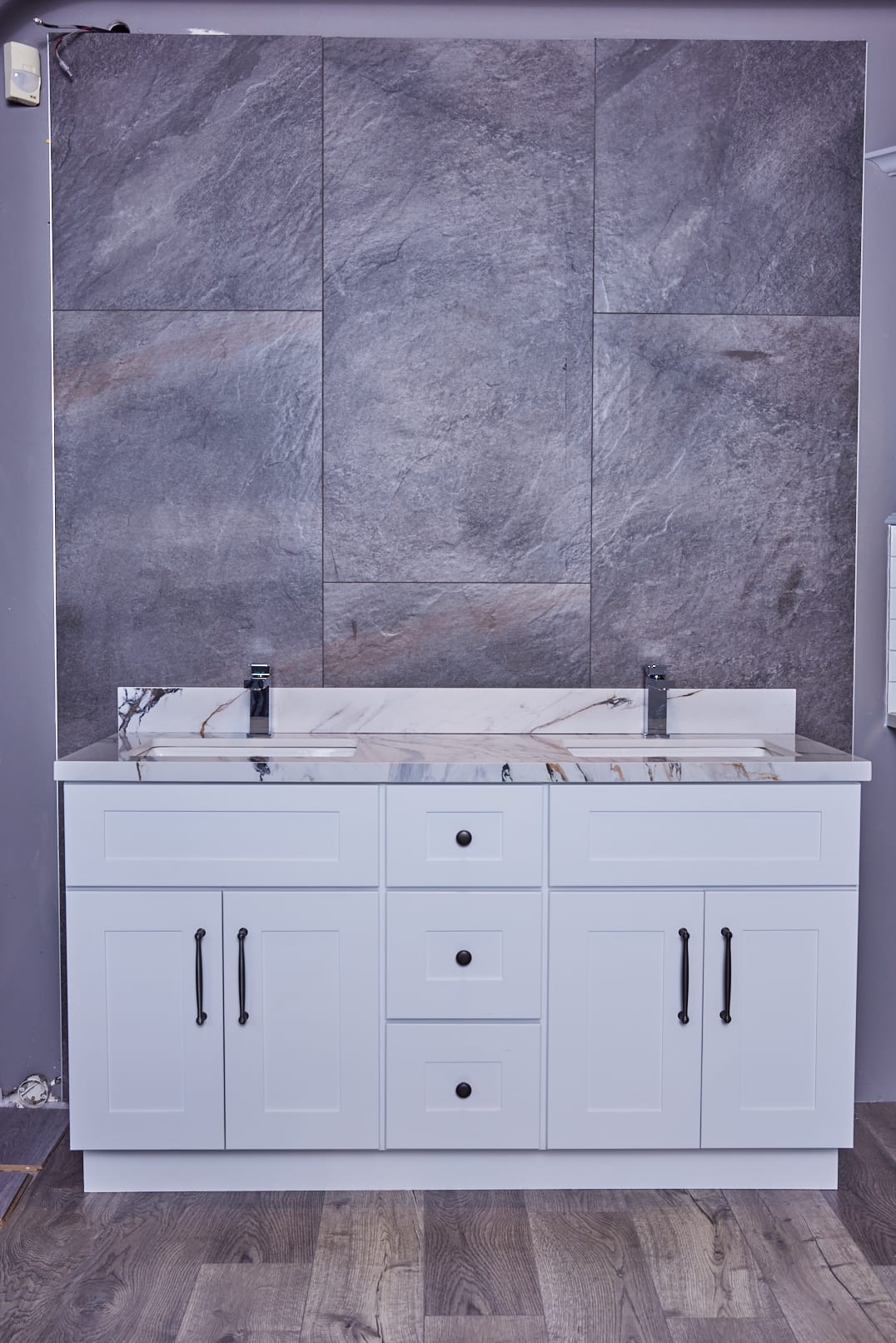 White bathroom vanity with marble countertop and gray tiled wall background.