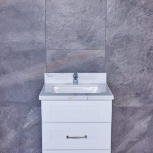 White bathroom vanity with sink against gray tiled wall.
