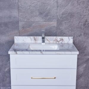 White bathroom vanity with marble countertop and gold handles against gray tiled wall.