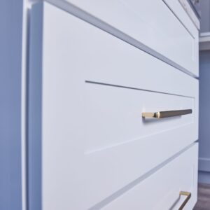 White kitchen drawers with sleek gold handles.