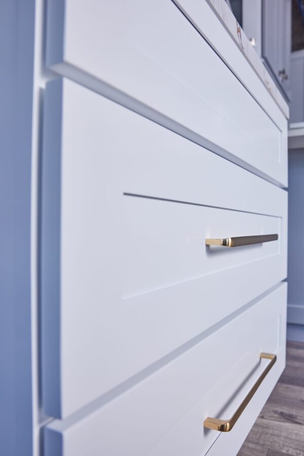 White kitchen drawers with sleek gold handles.