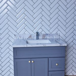 Blue bathroom vanity with marble countertop and herringbone tile wall.