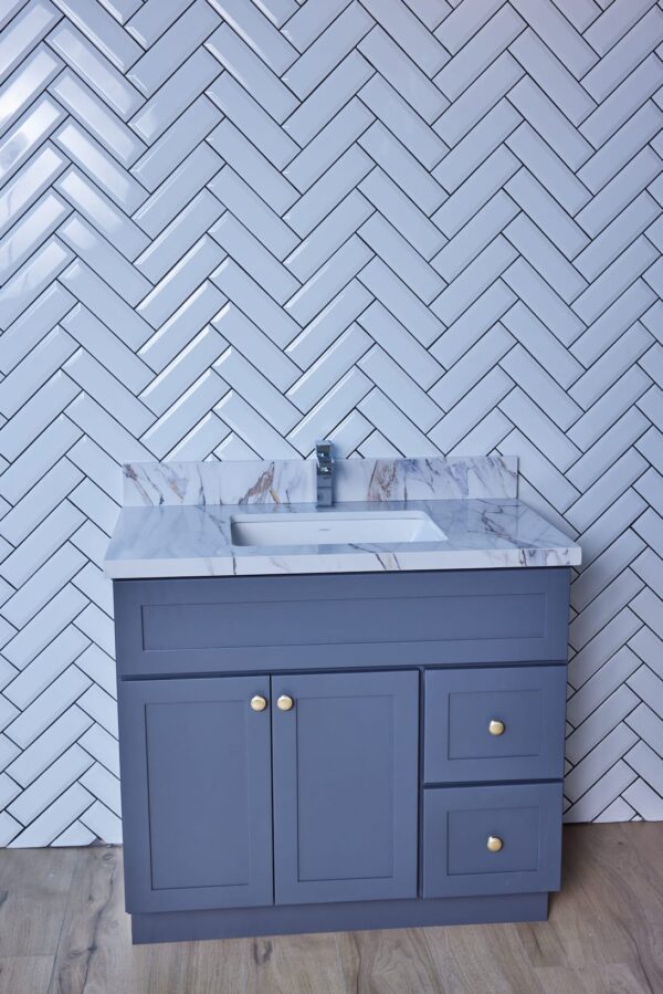 Blue bathroom vanity with marble countertop and herringbone tile wall.